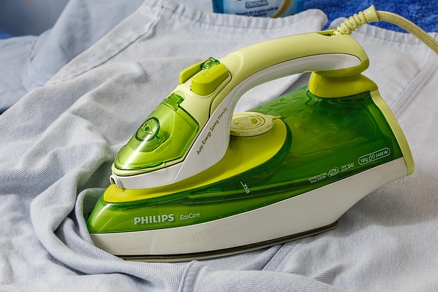 Green and white steam iron resting on fabric
